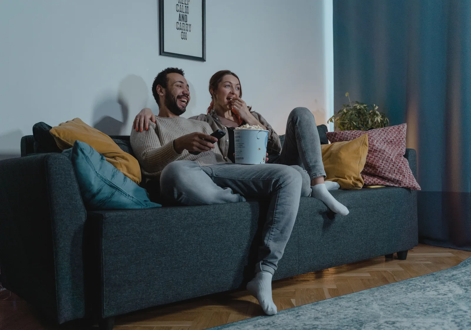 Par koser seg med popcorn og film i sofaen hjemme