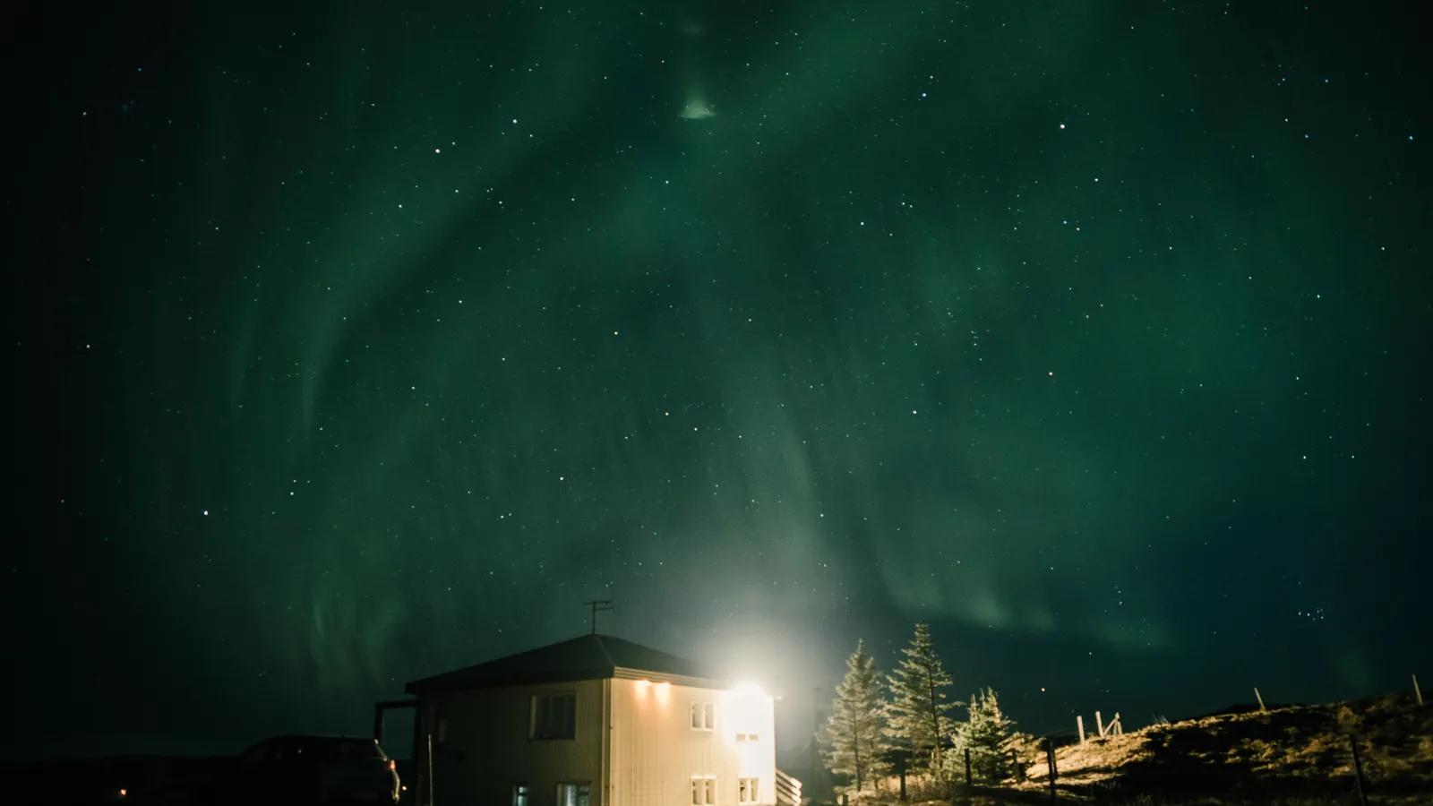 Nordlys over opplyst hus en vinternatt