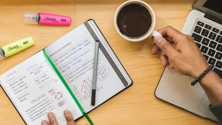 Notatbok med kriterier, kaffe og laptop under sammenligning